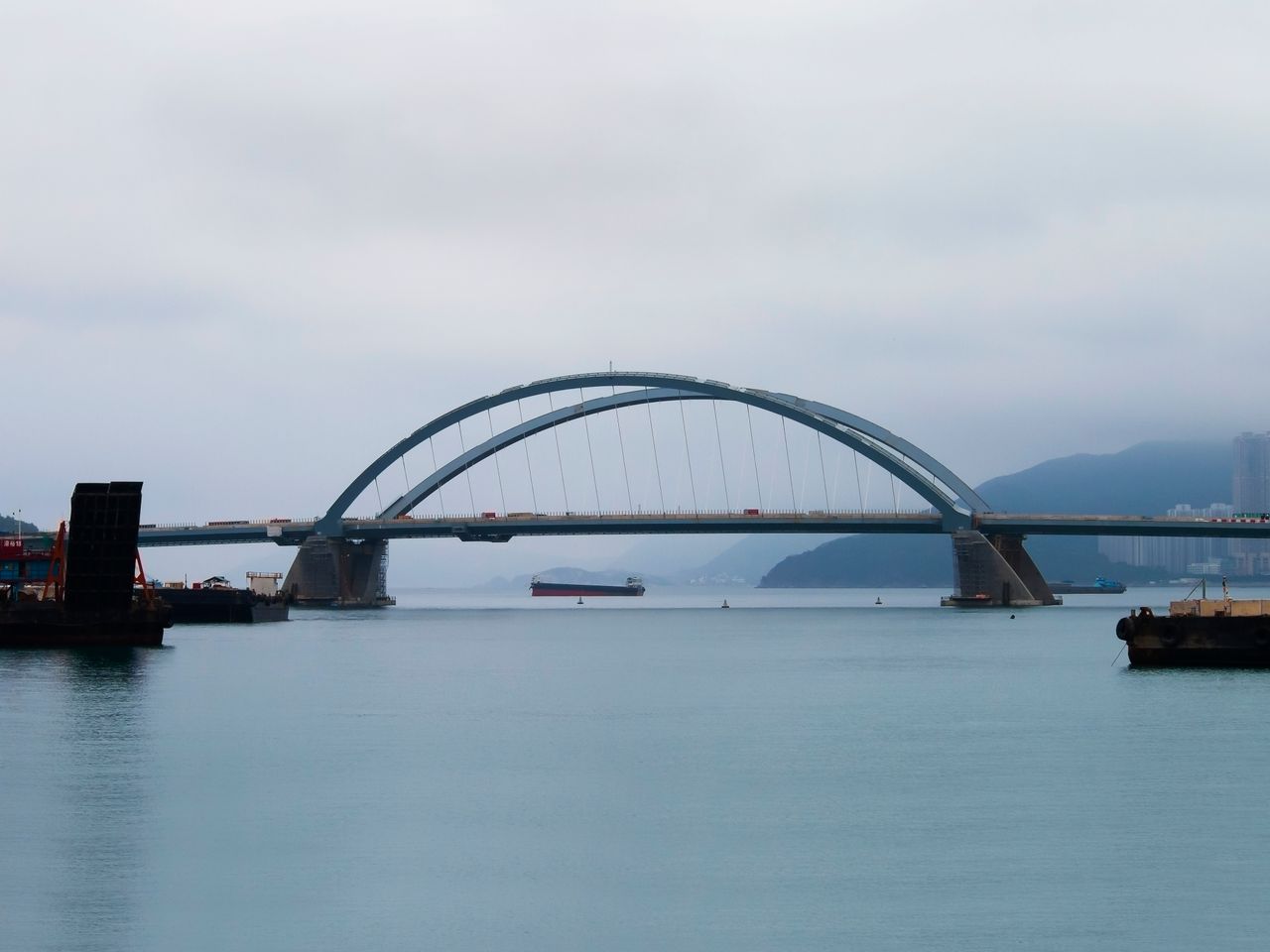 Bridge spanning across calm waters with a foggy backdrop, creating a serene cityscape.